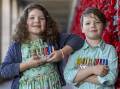 Mathilda Berry, 8 and brother Lucas, 6, hold aloft their family's war medals. Picture by Gary Ramage