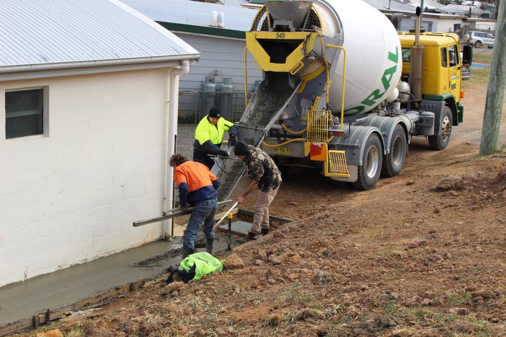 SHOWGROUND: Greg Moore pours concrete for new drainage.