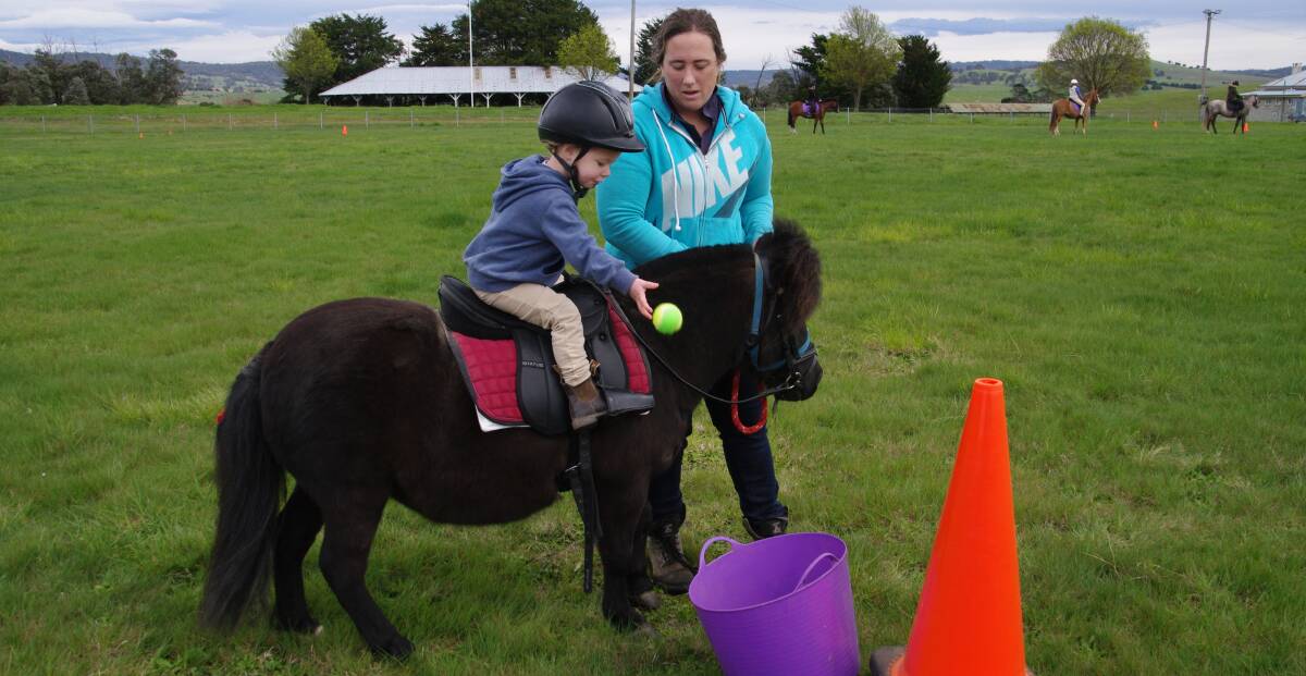 SADDLE TECHNIQUE: Delegate Pony Club junior rider, Aspen Cameron puts ball in bin at Sunday's Pony Club rally day, assisted by Sinead Cameron.