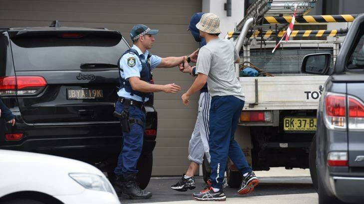 Two men try to get into a home during a raid in Merrylands. Photo: Nick Moir