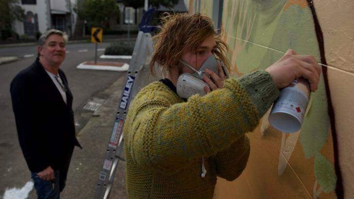 Dale Chaffey watches street artist Birdhat complete a mural on the side of his house  and cafe in Lewisham. Photo: Wolter Peeters