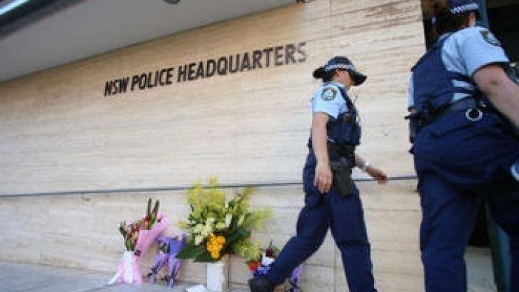 Police officers leave flowers outside police headquarters in Parramatta. Photo: James Alcock