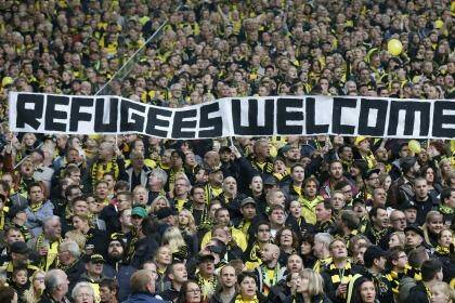 FILE - In this Oct. 25, 2014 file photo Dortmund supporters hold a banner prior the German first division Bundesliga soccer match between BvB Borussia Dortmund  and Hannover 96 in Dortmund, Germany. Traditional rivalries are being set aside for common cause as German football clubs and fans show their support across the country?s stadiums for refugees fleeing war and poverty. (AP Photo/Frank Augstein, file) Photo: Frank Augstein