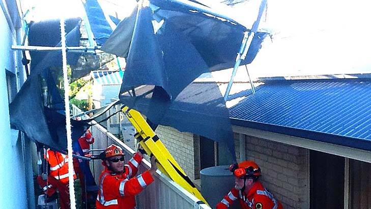 SES volunteers retrieve a trampoline from the roof of a house. Photo: SES