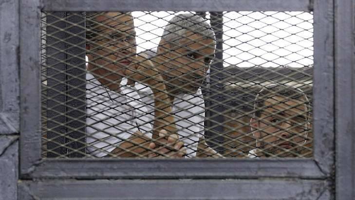 Al Jazeera journalists (L-R) Peter Greste, Mohammed Fahmy and Baher Mohamed stand behind bars at a court in Cairo June 1, 2014. Photo: Reuters