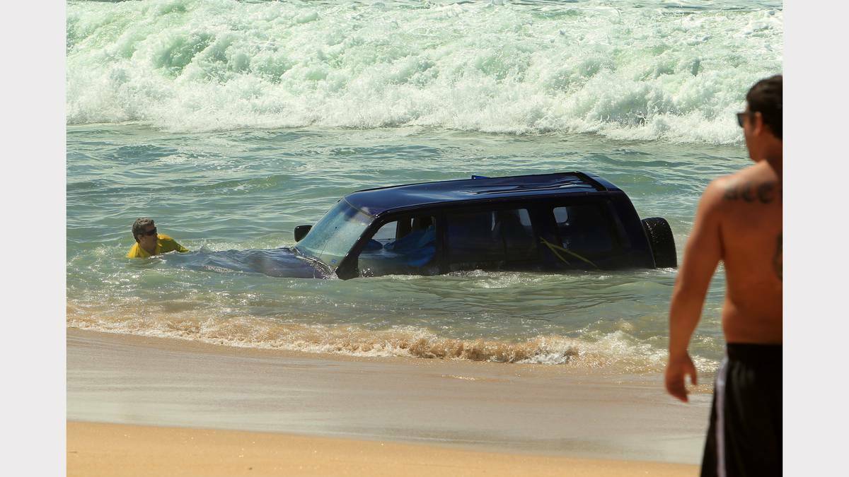Police, towing workers and locals with the abandoned four-wheel drive on Stockton Beach on Monday afternoon. Photo: JONATHAN CARROLL