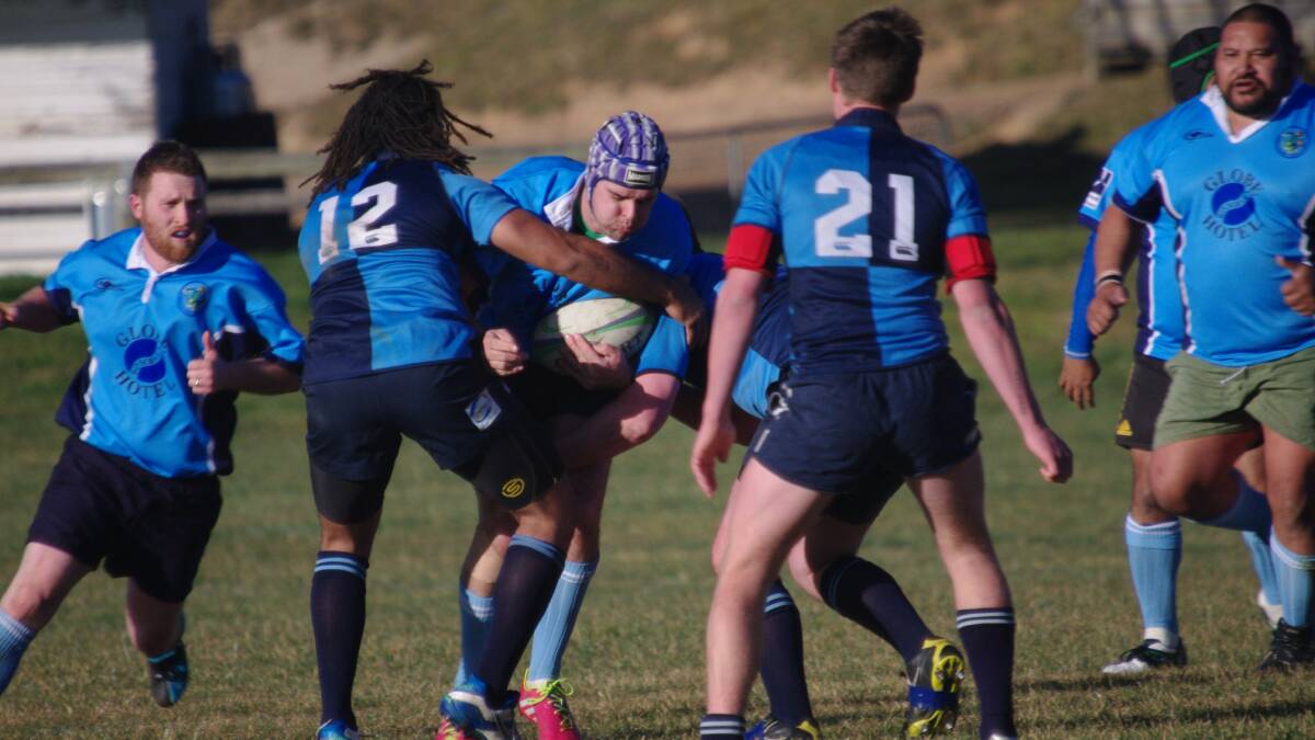 A Bombala Bluetongues player gets jammed by three Broulee Dolphins in Saturday’s disappointing home game.