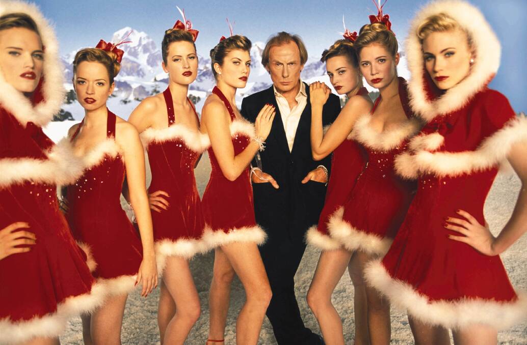 Bil Nighy laps up the attention from his santa little helpers in Love Actually.  Picture supplied by Universal studios.