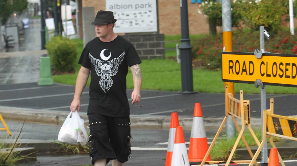 Tattooist Glenn Flowers walks past road closure signs at Albion Park. Picture: GREG TOTMAN