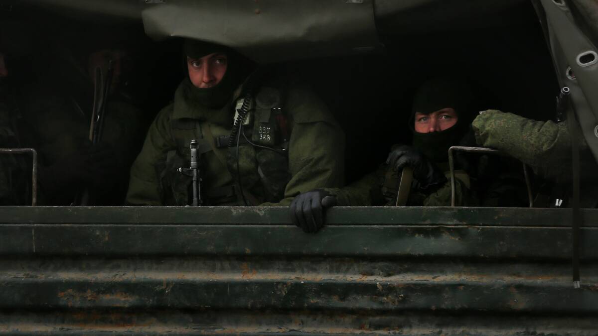 Armed Russian troops peer out the back of Russian military trucks as they are transported in a convoy heading north of Simferopol, Crimea. Photo: Kate Geraghty