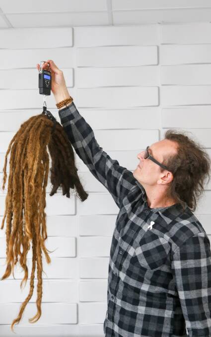 WEIGHT LIFTED: Maris Depers admires his 20-year-old dreadlocks while they are being weighed. The long locks were given the chop on Saturday. Pictures: Adam McLean