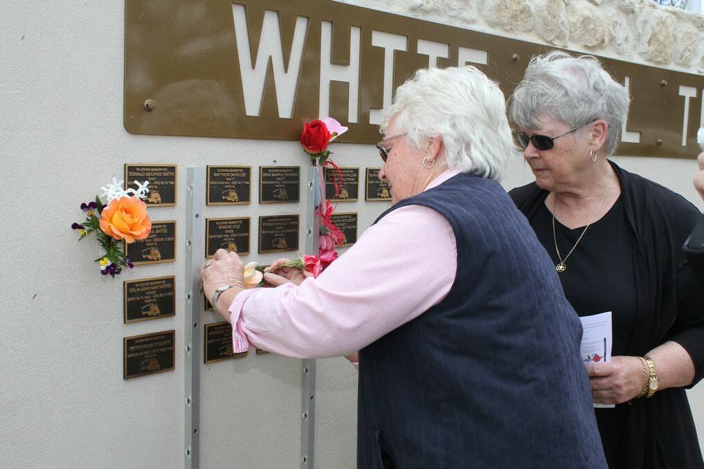 Vicki Courtney and Lyn Young place a rose on the plaque of their brother Robert Spurling at the White Hill Truck Drivers Memorial at Murray Bridge.