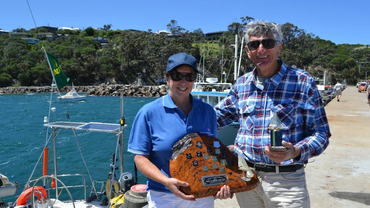 EDEN: Robyn Malcolm (left) from the Twofold Bay Yacht Club presents Rolex Sydney Hobart retiree Jim Clayton, skipper/owner of Black Adder, with the trophy for being the first retiree into Eden. 