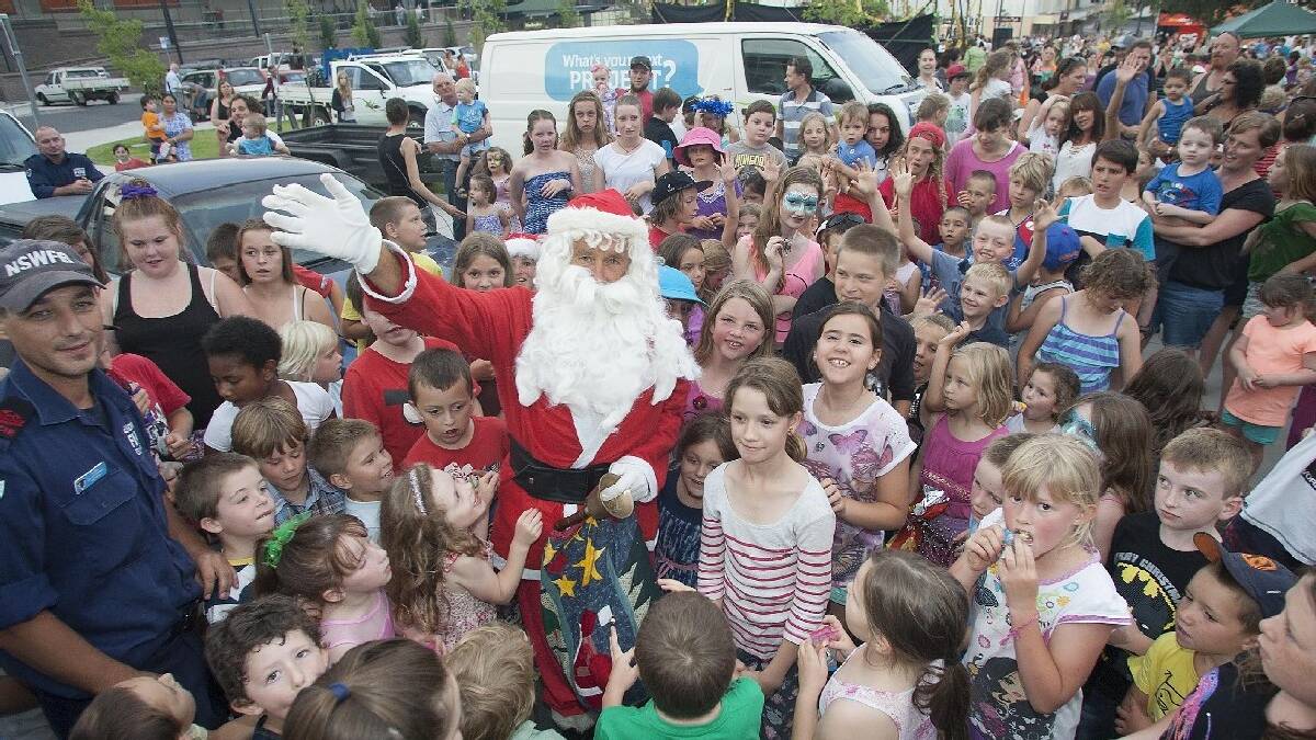 BEGA: Santa is mobbed by children enjoying Christmas carols and the Bega Chamber of Commerce annual prize draw in Bega's Littleton Gardens.