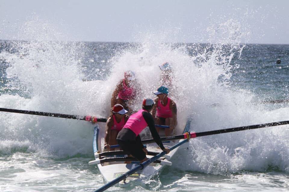 Bow down: The Batemans Bay Phoenix surf boat crew punch through a wave at the NSW State Surf Life Saving Championships recently. Image: Richard Black.