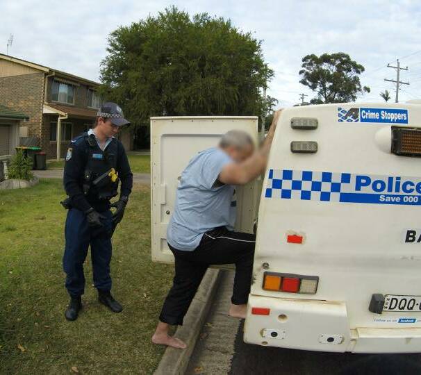 Arrested: Michael Brodribb is loaded into a police paddy wagon outside his Surf Beach home on Thursday. Picture: NSW Police