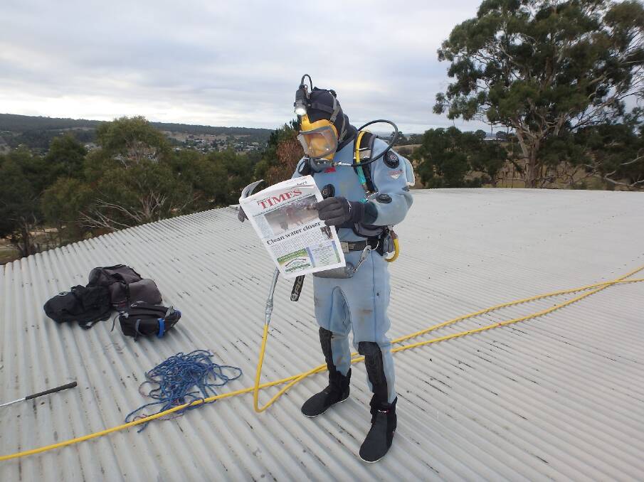 CLEAN WATER: One of the professional divers called in to vacuum the Bombala water holding tank reads his copy of the Bombala Times.