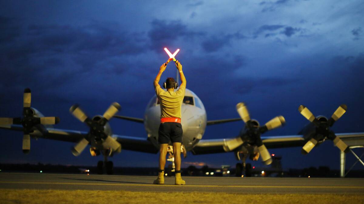 A ground controller guides a Royal Australian Air Force AP-3C Orion on the tarmac upon its return from a search for Malaysian Airlines flight MH370 over the Indian Ocean, at RAAF Base Pearce north of Perth, March 24, 2014 in Bullsbrook, Australia. Picture: Getty