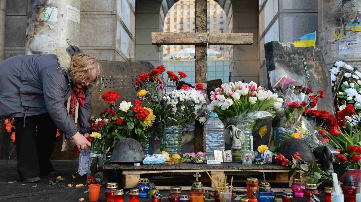 A woman places flowers at a makeshift shrine to the anti-government demonstrators killed in clashes with police in Independence Square in Kiev. Picture: Getty Images