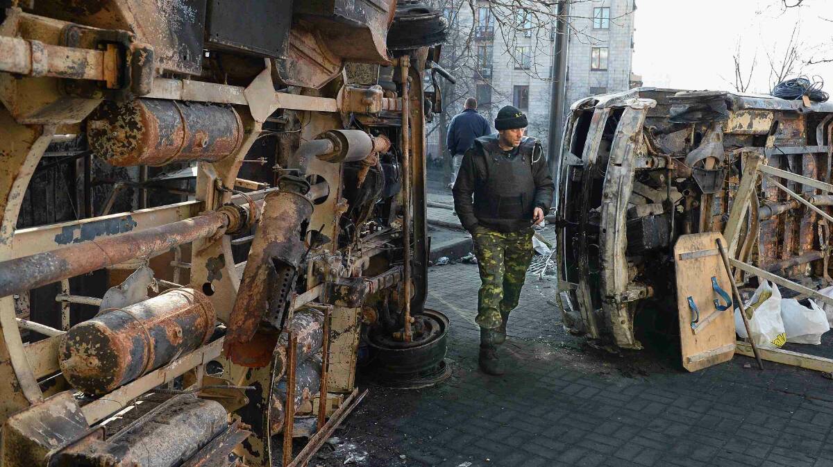 Anti-government protesters walk past burnt out vehicles near to front line barricades following clashes with police in Independence square in Kiev. Picture: Getty Images
