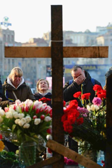 People react at a makeshift shrine to the anti-government demonstrators killed in clashes with police in Independence Square in Kiev. Picture: Getty Images