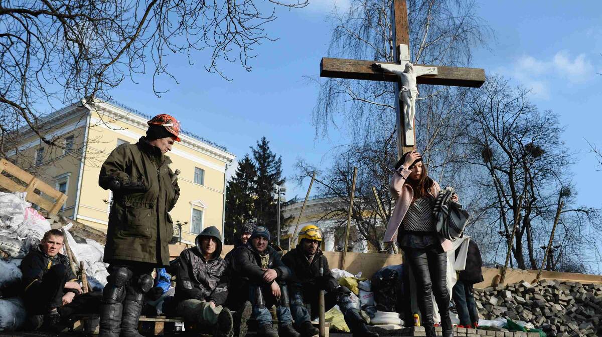 Anti-government protesters stand next to a cross near to front line barricades in Independence Square in Kiev. Picture: Getty Images