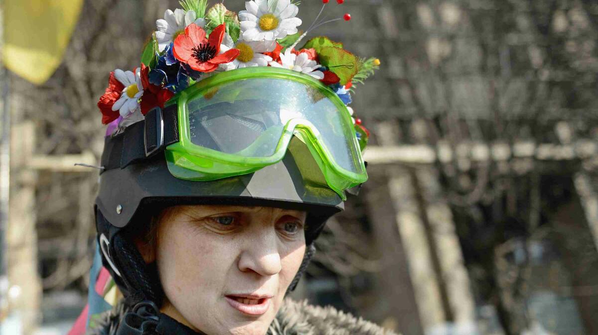  A female anti-government demonstrator wears flowers in her helmet in Independence square in Kiev. Picture: Getty Images